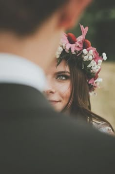 a close up of a person wearing a flower headpiece and looking into the distance