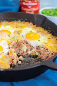 two eggs are being cooked in a skillet on a blue towel next to other dishes