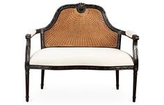 an antique chair with wicker back and white cushion on the seat, against a white background