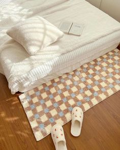 a pair of slippers sitting on top of a wooden floor next to a bed