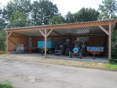 several tractors are parked under a covered garage