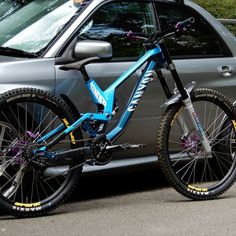 a blue mountain bike parked next to a silver car