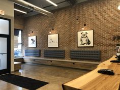 an office with brick walls and benches in front of the windows, along with pictures on the wall