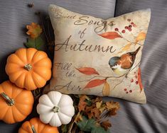 an autumn pillow and some pumpkins on a couch with the words sweet songs of autumn written on it