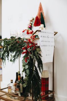 a christmas tree with red berries and greenery in front of a sign that says welcome to the holiday season