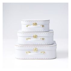 three white suitcases stacked on top of each other with gold handles and rivets