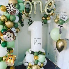 the balloon arch is decorated with jungle animals and balloons that spell out'one '