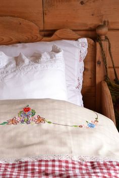 a bed with white pillows and red checkered bedspread on top of it