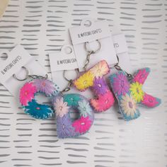 three key chains with flowers on them sitting on a table