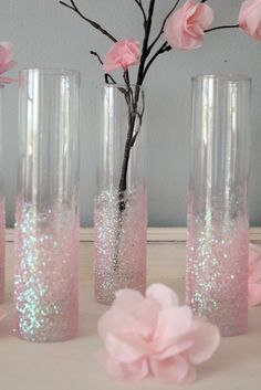 two vases with pink flowers in them and one has glitter on the bottom, while the other is filled with water