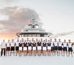 a group of men standing next to each other in front of a large white boat