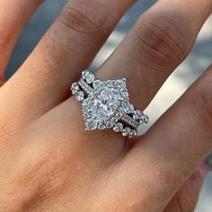 a woman's hand with a diamond ring on top of her finger and an engagement band