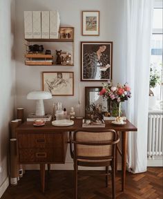 a desk with some pictures on the wall above it and a chair next to it