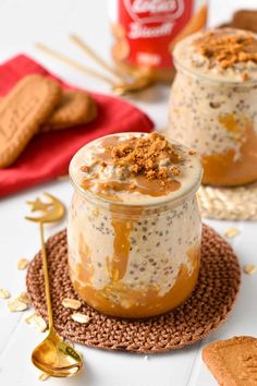 two jars filled with food sitting on top of a table next to crackers and spoons