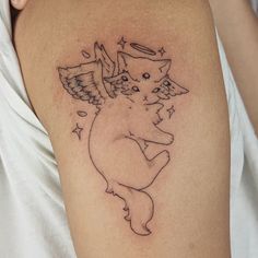 a small tattoo on the arm of a girl with an angel cat and stars around her