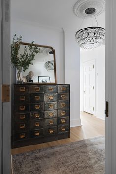 a dresser with many drawers and a mirror in the corner next to an entryway