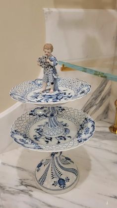 three blue and white plates stacked on top of each other with a figurine in the middle