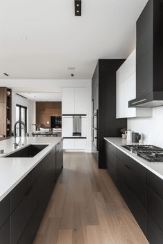 a kitchen with black and white cabinets, wood flooring and an island in the middle