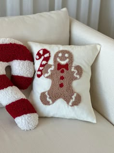 a white couch with a red and white pillow on top of it next to a christmas decoration