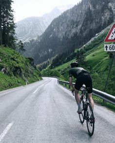 a bicyclist is riding down the road in front of a speed limit sign