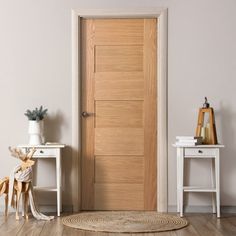 a wooden door in a white room with two small tables and a rug on the floor