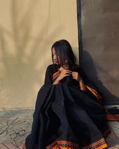 a woman sitting on the ground in a black dress