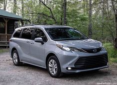 a silver toyota highland parked in front of a cabin on the side of a road