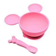 a pink mickey mouse shaped bowl with spoons next to it on a white background