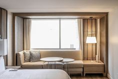 a hotel room with a bed, couch and coffee table in front of a large window