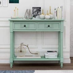 a green table with two drawers and pictures on the wall above it, next to a white couch