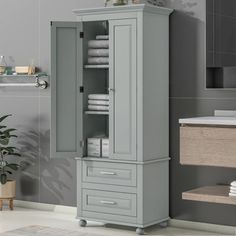 a bathroom with a gray cabinet and white towels on the shelf in front of it