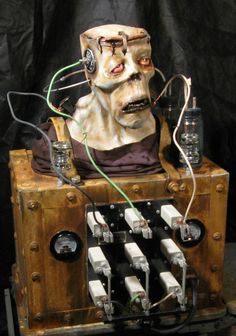 a creepy mask sitting on top of a wooden box filled with electrical wires and plugs