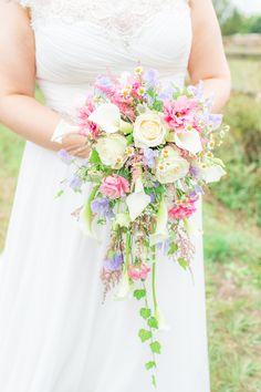 a woman holding a bouquet of flowers in her hands and wearing a white dress with lace on it