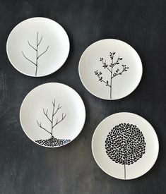 three plates with black and white designs on them, one has a tree in the middle