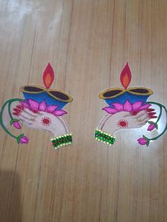 two hand holding a lit candle on top of a wooden table with pink flowers and green leaves