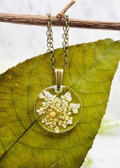 This beautiful floral mustard seed necklace is perfect for any occasion!  Share your faith and your love of nature everywhere you go. This beautiful handmade resin necklace makes the perfect gift for a loved one, a best friend, or just a reminder of your own inner beauty and faith.  Necklace is handmade with resin, real flowers, mustard seeds, and an antique bronze chain.  Chain Length: 18 inches long  Chain Width: 1.5 mm Antique Bronze chain with lobster clasp Please contact me if you have any questions or requests. Due to the handmade nature of the resin process no two necklaces will ever be exactly identical. Please keep in mind that there may be some minor imperfections in the resin, such as tiny air bubbles SHOP DESCRIPTION: Resin jewelry has endless possibilities and I love creating Yellow Necklace With Birth Flower Pendant, Yellow Birth Flower Pendant Necklace, Delicate Yellow Necklace For Gift, Yellow Resin Jewelry As A Gift, Yellow Resin Jewelry As Gift, Yellow Resin Jewelry For Gifts, Nature-inspired Yellow Necklace For Gifts, Yellow Resin Jewelry Gift, Yellow Nature-inspired Necklace For Gifts