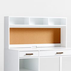 a white desk with two drawers and a cork board on the top, in front of a white wall