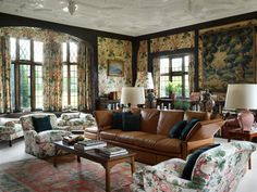 a living room filled with lots of furniture and windows covered in floral wall coverings