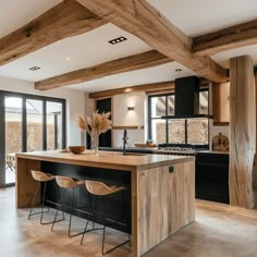 a large kitchen with wooden beams and black cabinets, an island countertop and bar stools