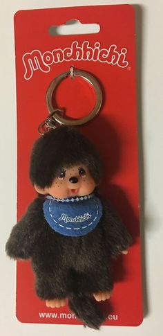 a black bear keychain with a blue bib around it's neck