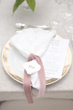 the table is set with white and gold plates, napkins, and silverware