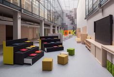 an office lobby with couches, tables and chairs in the foreground is a large television screen