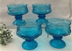 four blue glass goblets sitting next to each other