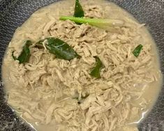 a bowl filled with noodles and greens on top of a tablecloth covered plate,