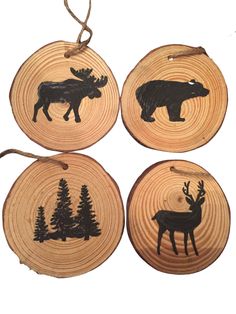 three wooden ornaments with moose and pine trees on them, one is hanging from a rope