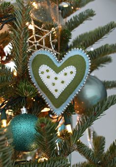 a green and white heart ornament hanging from a christmas tree