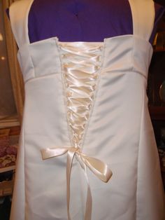 the back of a white dress with a bow at the waist and an attached sash