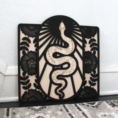 a wooden sign with a snake on it's side in front of a wall