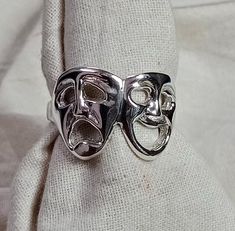 The Tragedy Mask Ring is an exquisite piece of jewelry that captures the essence of classic theatre in a silver design. This stunning statement ring features a double-faced, happy and sad mask, symbolizing the contrasting emotions of comedy and tragedy. Crafted with utmost attention to detail, this dainty silver ring is perfect for those seeking a unique accessory that adds character to any outfit. Whether you're a drama enthusiast or simply adore the arts, this lightweight ring is a must-have addition to your collection. Product Description - Material :- 925 Sterling Silver Style : Face Jewelry Care Instruction- Always: Apply lotion, cosmetics, hairspray and perfume before dressing in jewelry. When undressing, wipe each piece with a clean soft cloth to remove oils and perspiration. Store Clown Rings, Dainty Silver Ring, Tragedy Mask, Face Jewelry, Silver Mask, Clown Mask, Face Ring, Comedy And Tragedy, Two Face