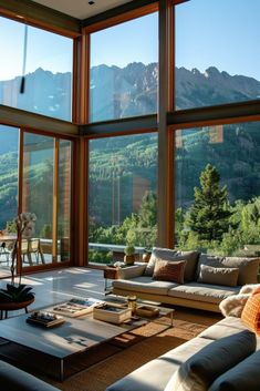 a living room filled with lots of furniture and large windows that look out onto the mountains